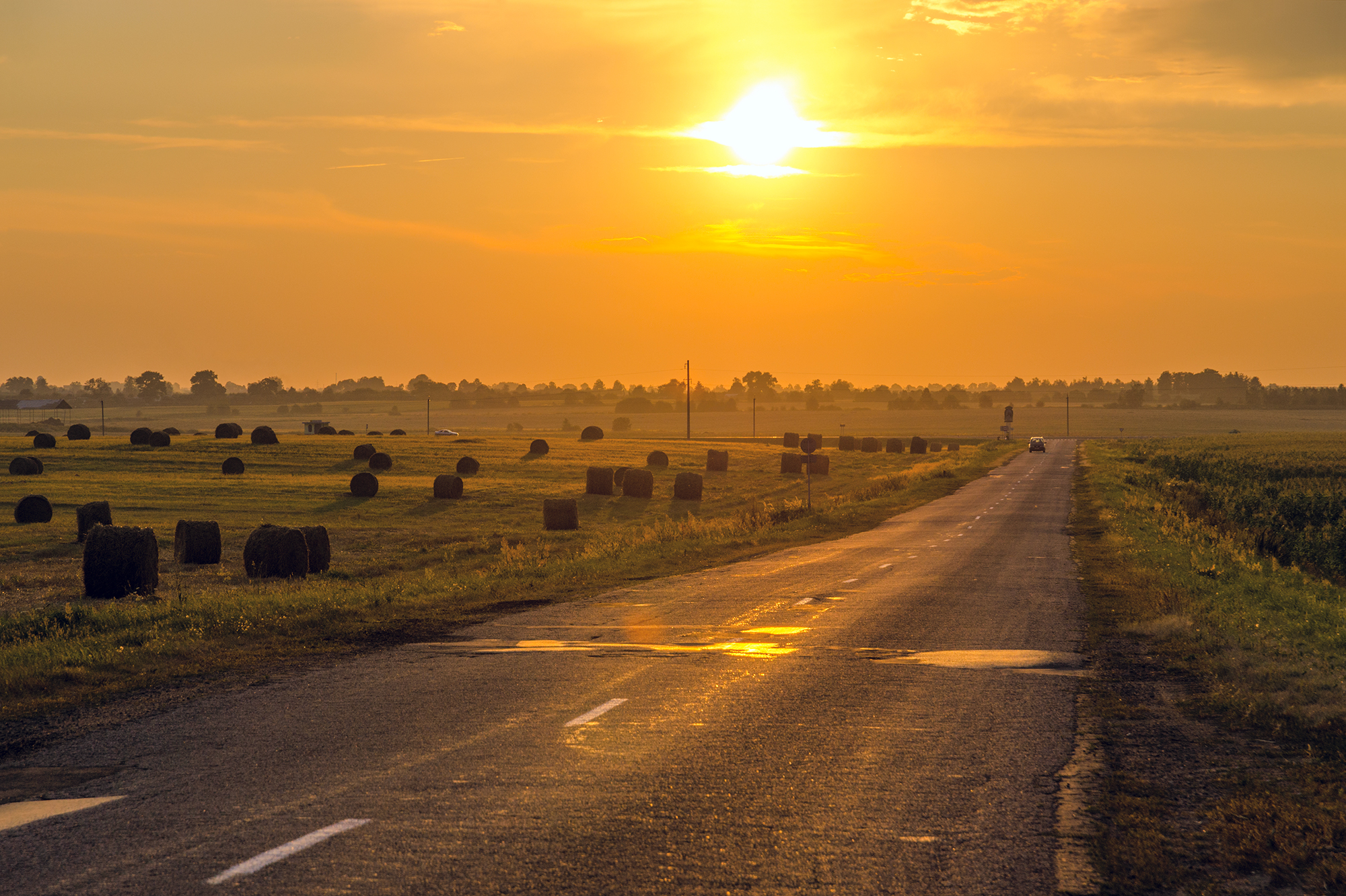 Rural road at sunset with hay bales